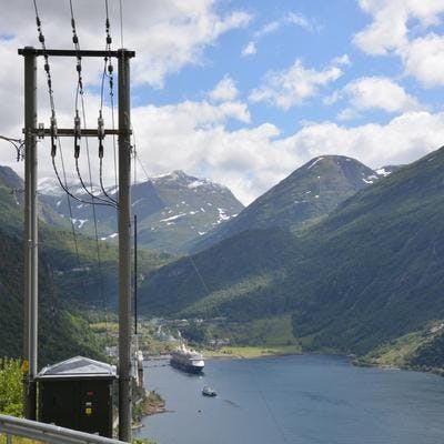 Nettmast med fjord, fjell og Hurtigruta i bakgrunnen.