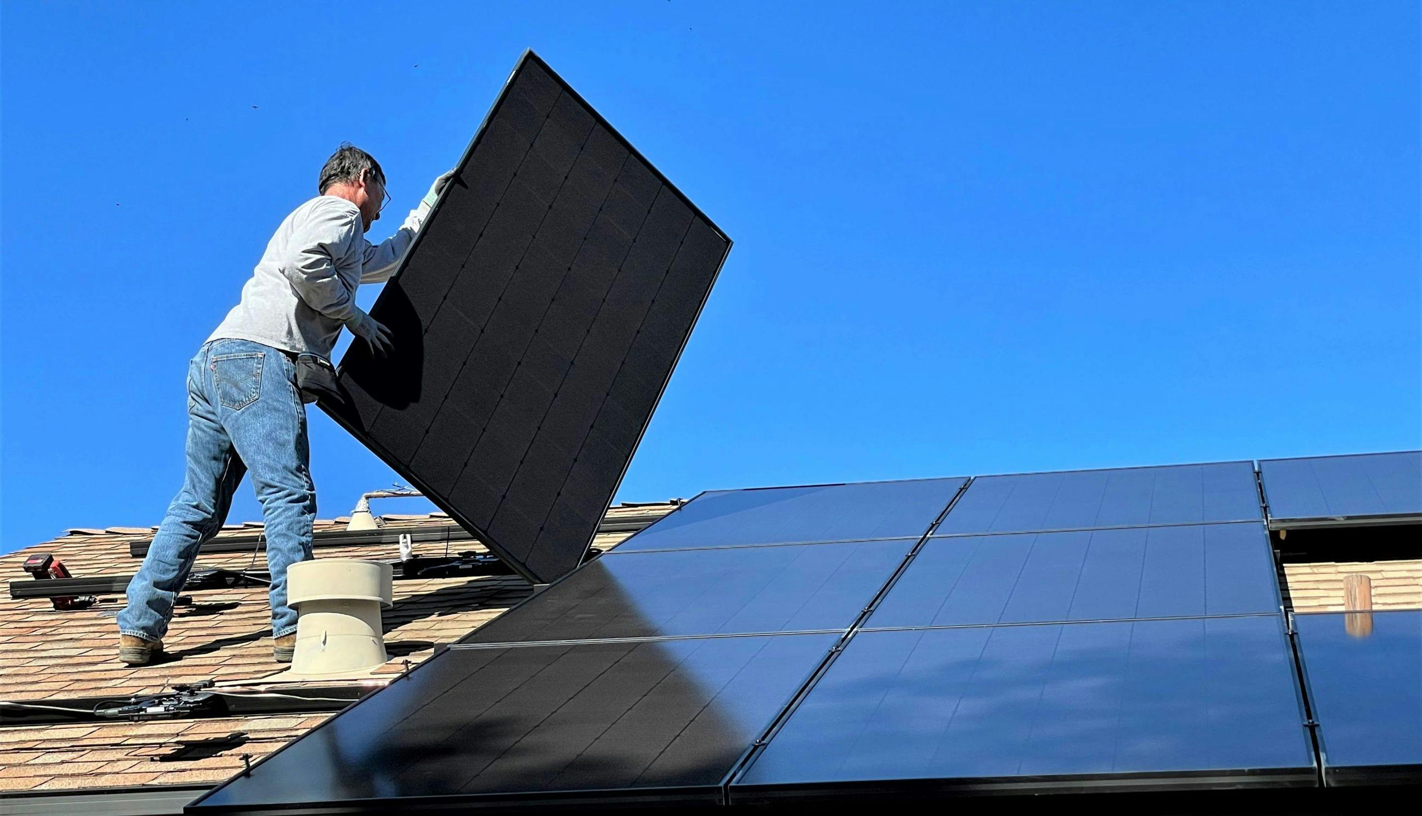 Mann som monterer solceller på tak.