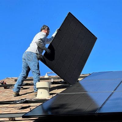 Mann som monterer solceller på tak.
