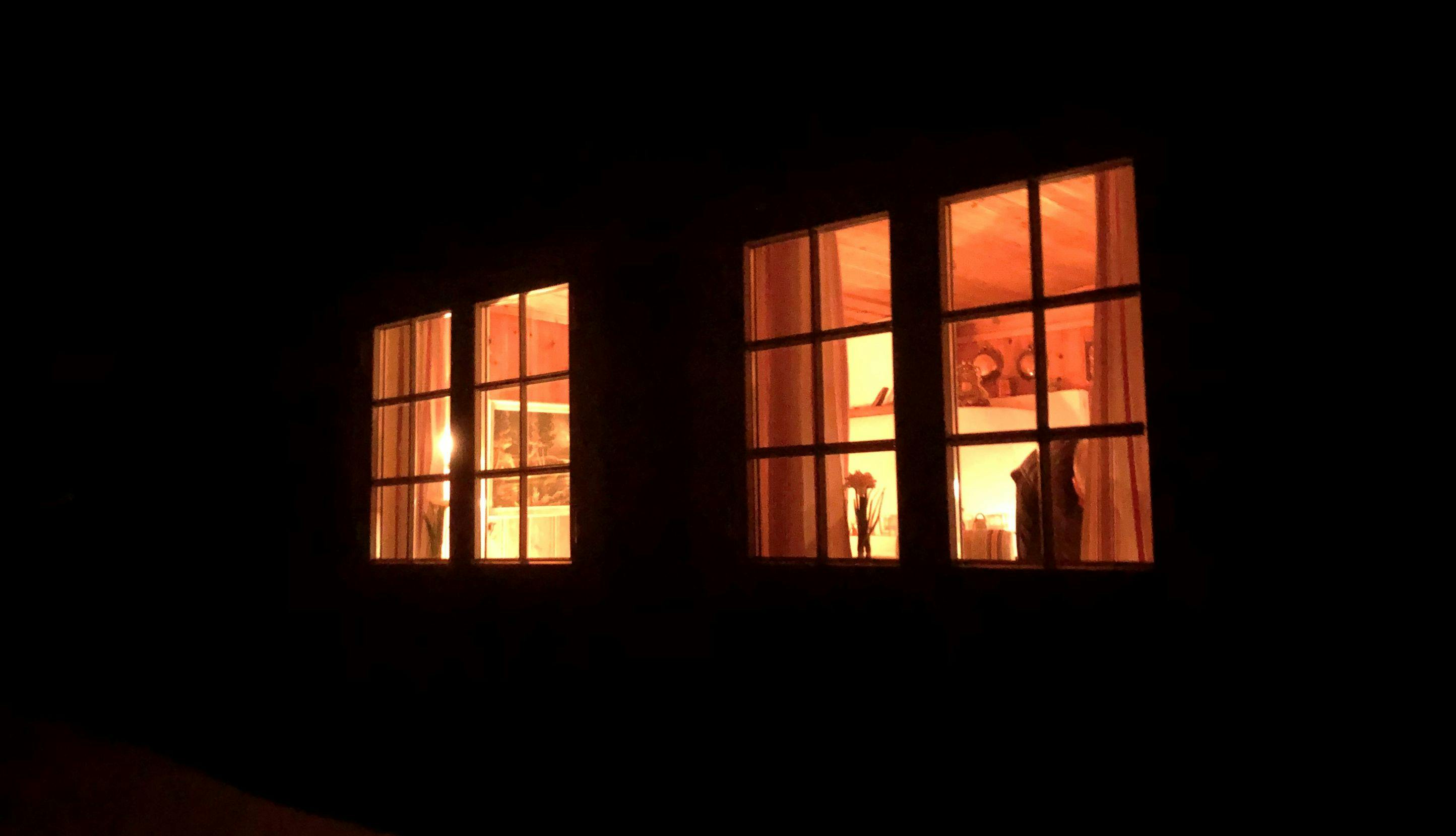Lys fra vinduer i hus sett utenfra.